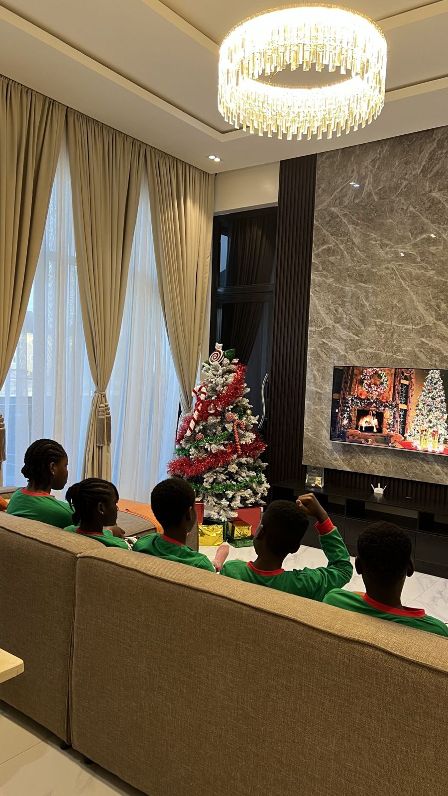 Children watching TV together on the sofa under the chandelier at Nimbus Nook