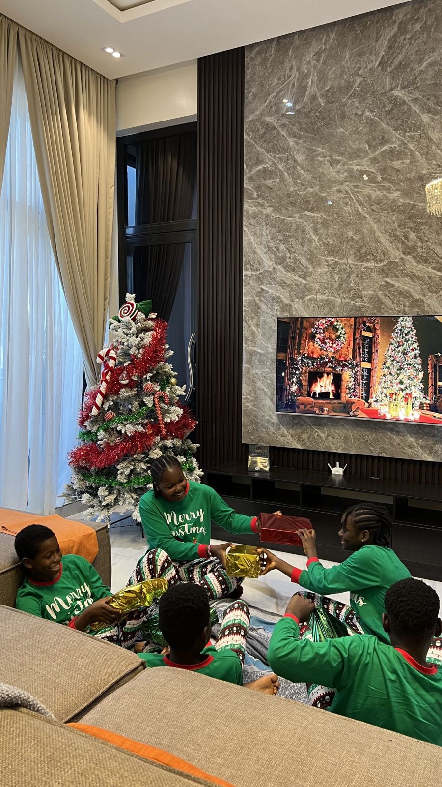 Children exchanging gifts in front of the marble TV wall at Nimbus Nook