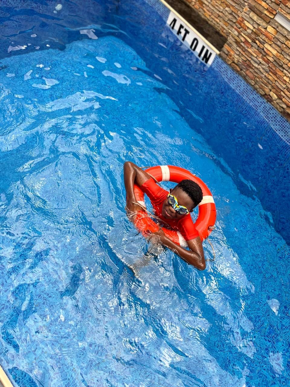 Child in goggles swimming with a lifebuoy in the Nimbus Nook pool