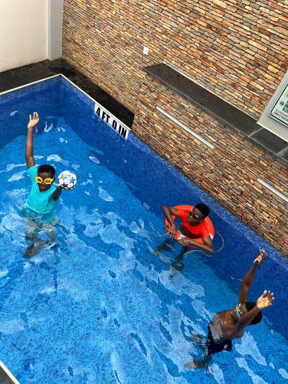 Children playing with a ball in the pool at Nimbus Nook Apartments, Ikeja GRA