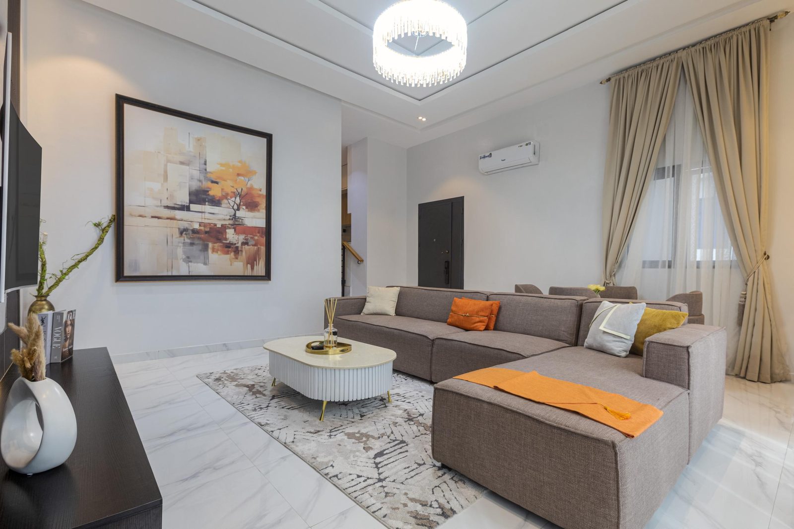 Living room with sectional sofa and artwork at Nimbus Nook shortlet apartments, Ikeja GRA